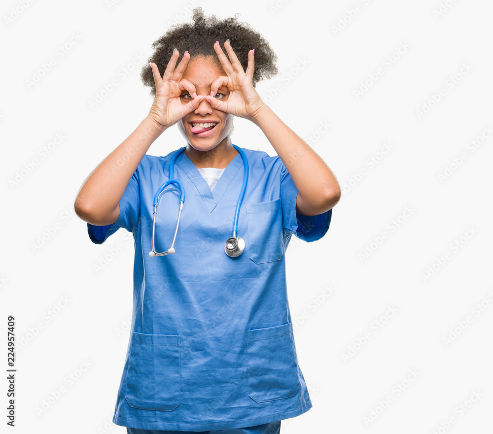 Young afro american doctor woman over isolated background doing ok gesture like binoculars sticking tongue out, eyes looking through fingers. Crazy expression. Young afro american doctor woman over isolated background doing ok gesture like binoculars sticking tongue out, eyes looking through fingers. Crazy expression.