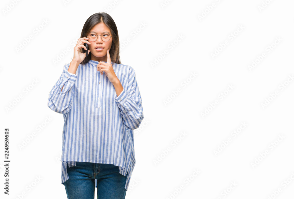Young asian woman speaking on the phone over isolated background serious face thinking about question, very confused idea Young asian woman speaking on the phone over isolated background serious face thinking about question, very confused idea