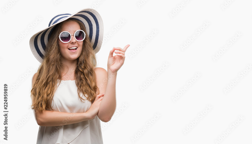 Young blonde woman wearing sunglasses and summer hat very happy pointing with hand and finger to the side Young blonde woman wearing sunglasses and summer hat very happy pointing with hand and finger to the side