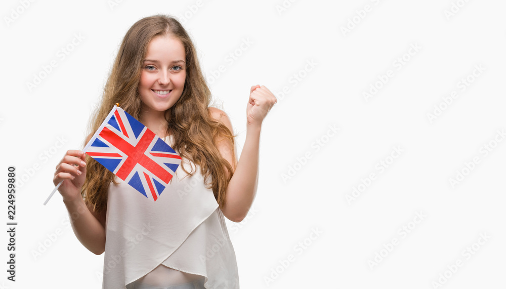 Young blonde woman holding flag of UK screaming proud and celebrating victory and success very excited, cheering emotion Young blonde woman holding flag of UK screaming proud and celebrating victory and success very excited, cheering emotion