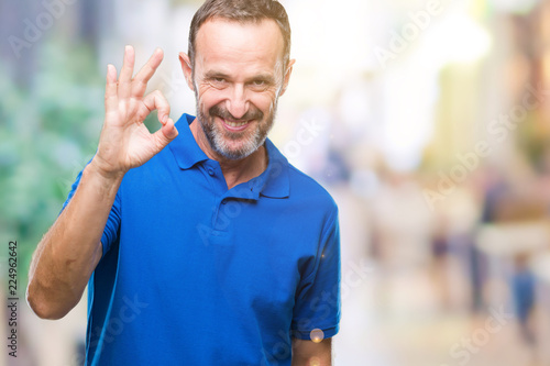 Middle age hoary senior man over isolated background smiling positive doing ok sign with hand and fingers. Successful expression.