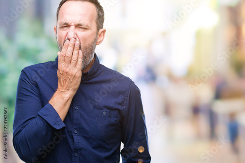Middle age hoary senior man over isolated background bored yawning tired covering mouth with hand. Restless and sleepiness.