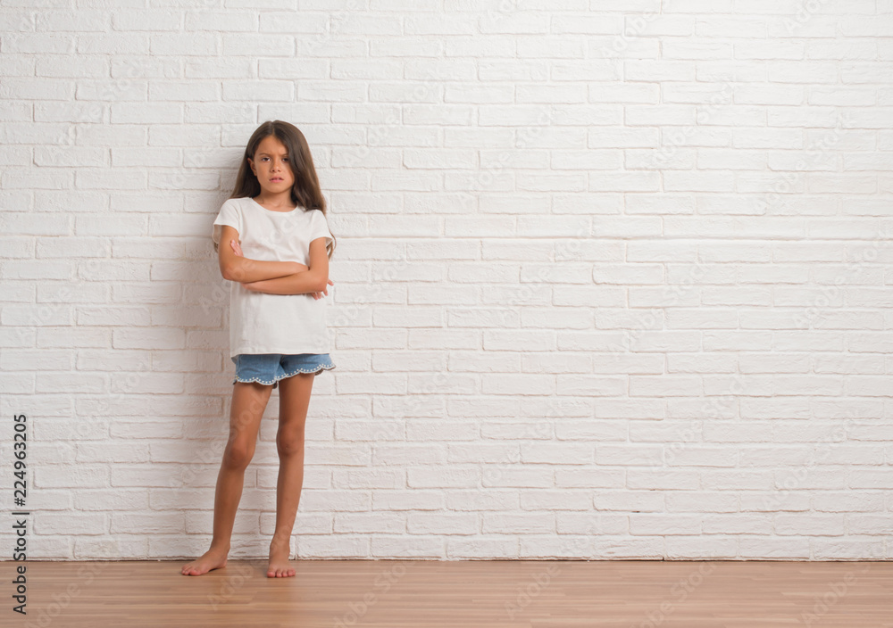 Young hispanic kid stading over white brick wall skeptic and nervous, disapproving expression on face with crossed arms. Negative person. Young hispanic kid stading over white brick wall skeptic and nervous, disapproving expression on face with crossed arms. Negative person.