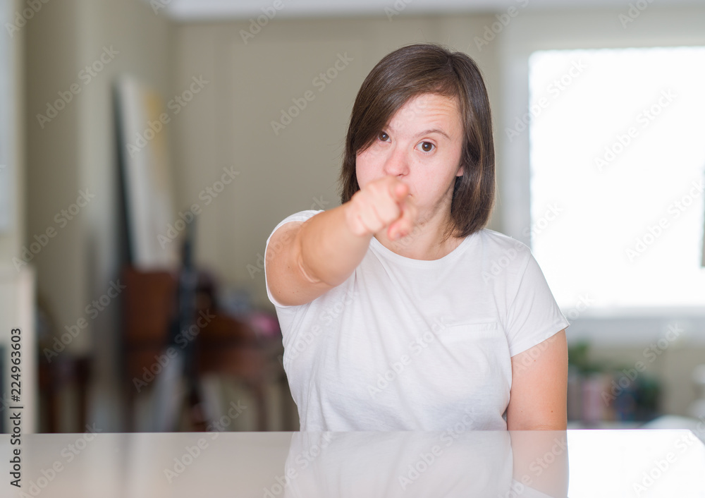 Down syndrome woman at home pointing with finger to the camera and to you, hand sign, positive and confident gesture from the front