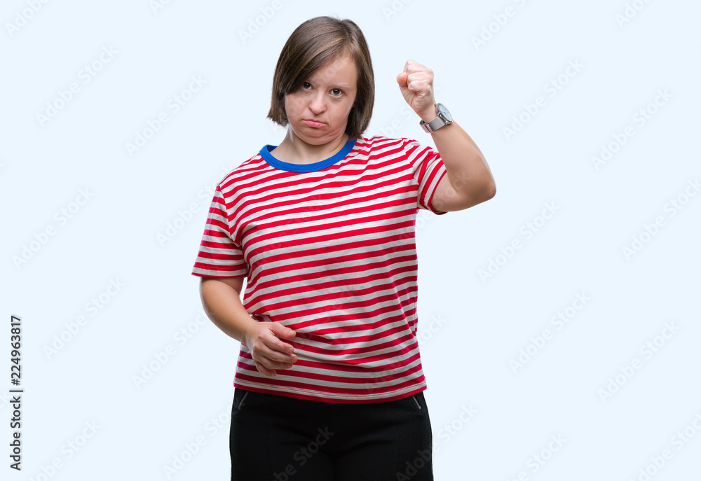 Young adult woman with down syndrome over isolated background angry and mad raising fist frustrated and furious while shouting with anger. Rage and aggressive concept. Young adult woman with down syndrome over isolated background angry and mad raising fist frustrated and furious while shouting with anger. Rage and aggressive concept.