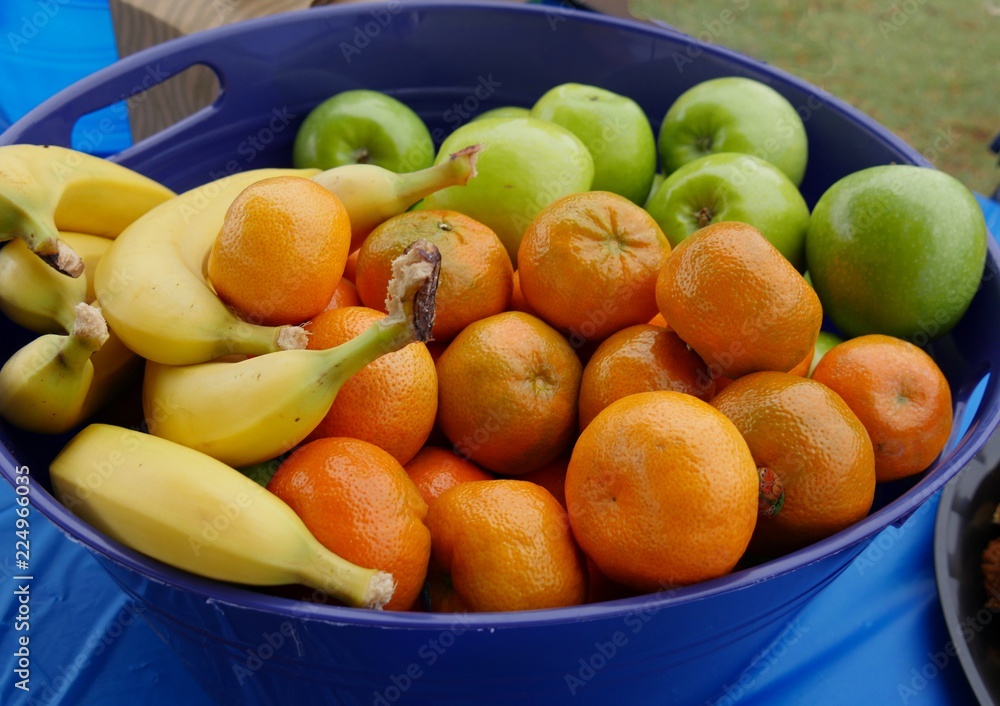 A tray of fresh tropical fruits including orange, apples, and ripe bananas A tray of fresh tropical fruits including orange, apples, and ripe bananas