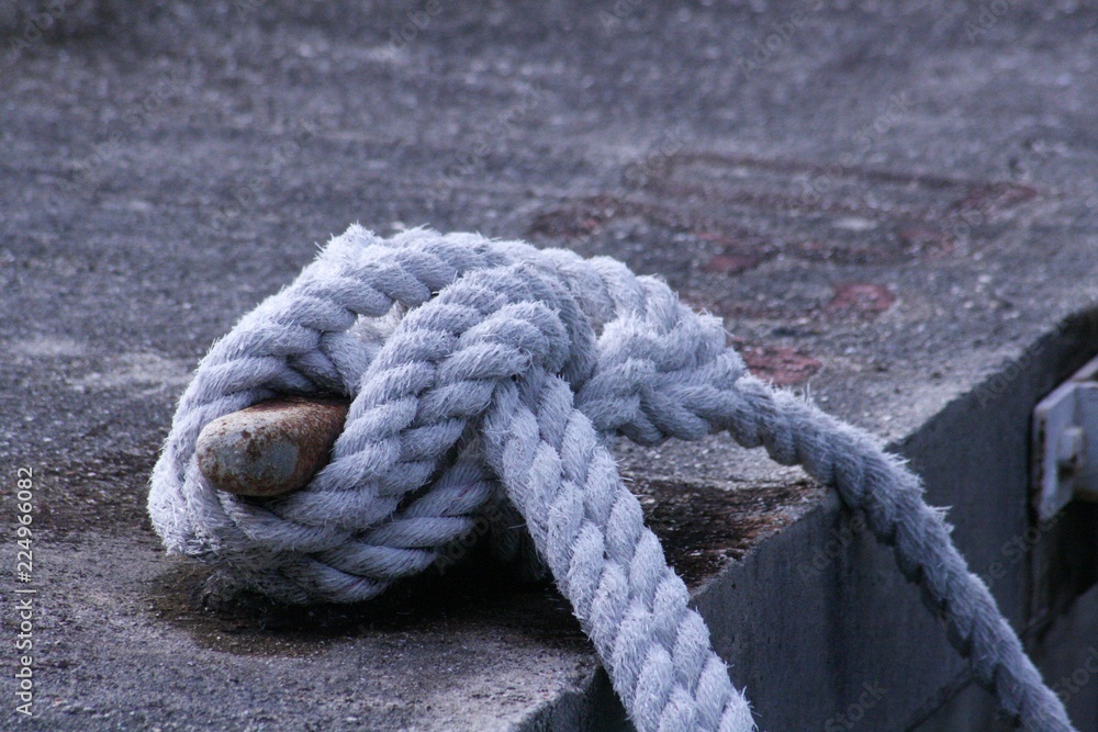  Thick braids of white rope tied to a mooring at a harbor