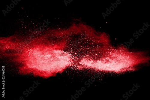 Red color powder explosion on black background.Freeze motion of red dust particles splashing.