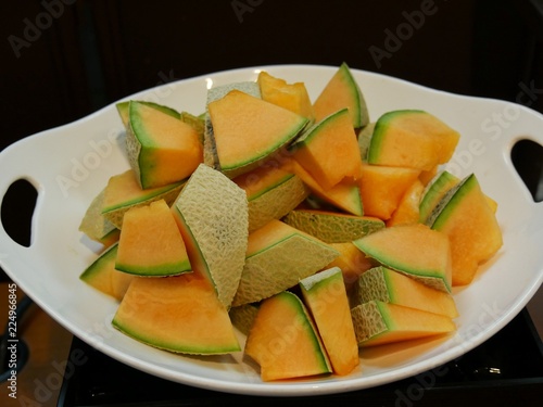 Slices of cantaloupe melon arranged in a round oval plate with handhold
