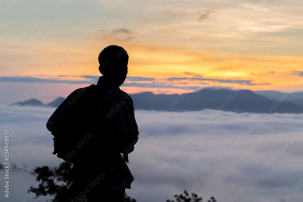 Traveler young man standing in the summer mountains at sunset and enjoying view of nature.