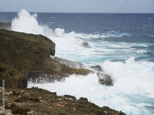 Huge waves splash against sharp rocks in a tropical island