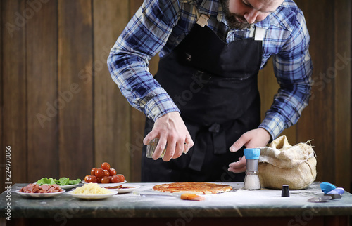 man preparing a pizza, knead the dough and puts ingredients