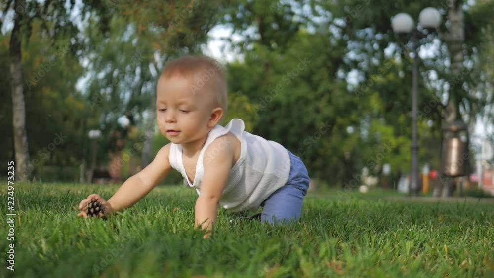 Cute toddler boy, sitting on the grass at park. Cute toddler boy, sitting on the grass at park.