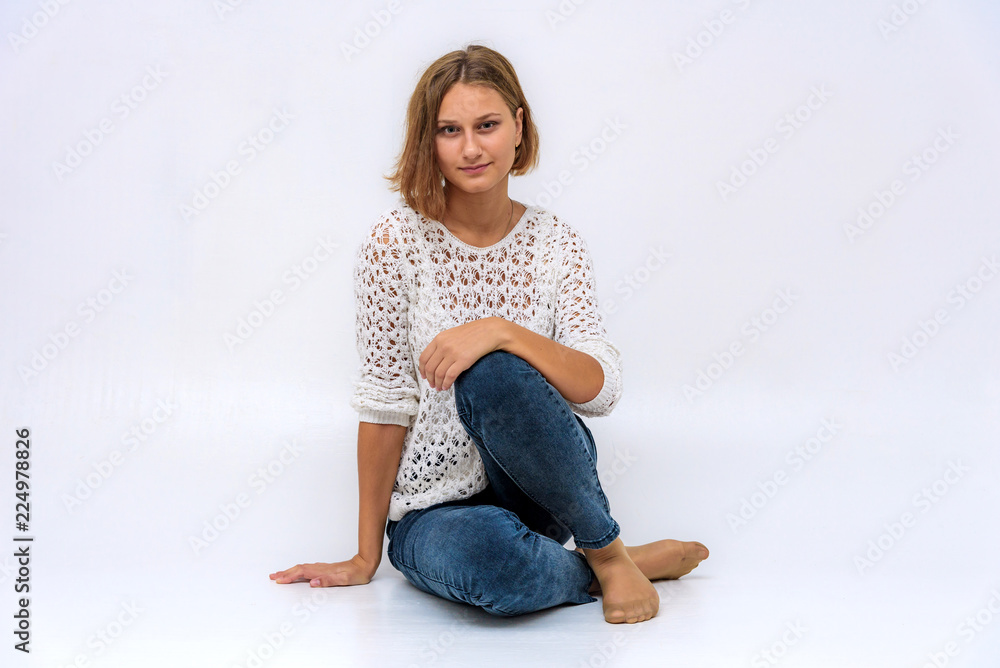 portrait of a young beautiful girl on a white background sitting on the floor. portrait of a young beautiful girl on a white background sitting on the floor.
