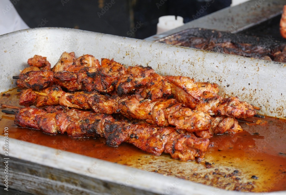 Chicken barbecue in skewers inside a tray swimming in its own juices at a street food stall