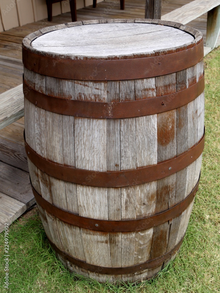 Rustic wooden barrel on a grassy ground, leaning against wooden floors Rustic wooden barrel on a grassy ground, leaning against wooden floors