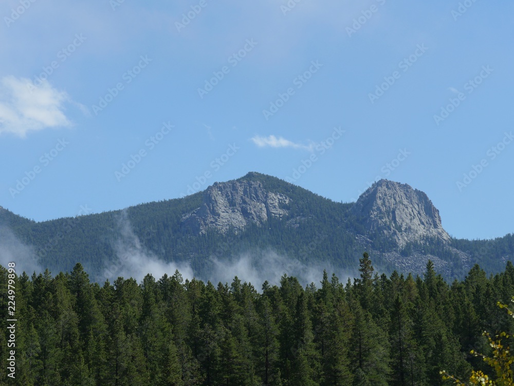 Mystical view of Colorado mountains with mist rising above the green trees