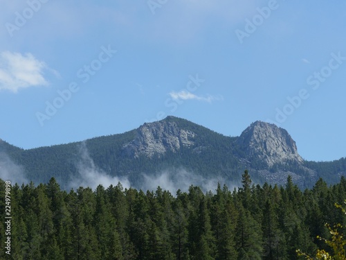 Mystical view of Colorado mountains with mist rising above the green trees