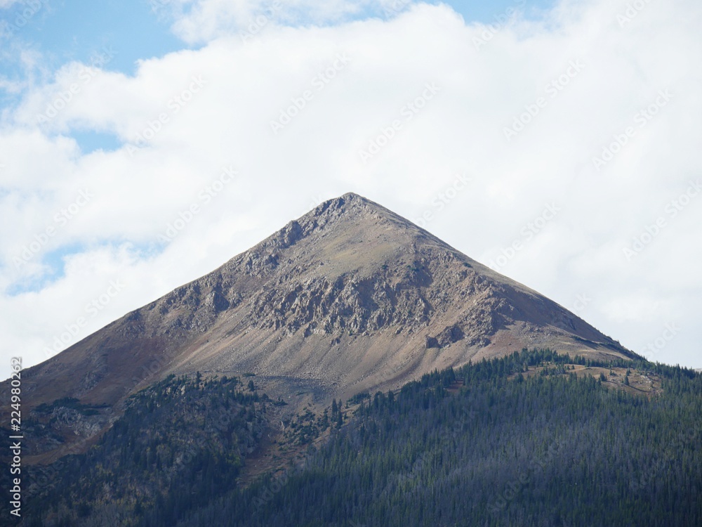 Close up of a mountain peak in Loveland Pass, Colorado with green trees at its foot