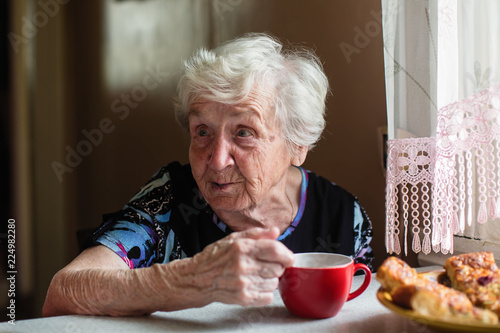 An elderly woman has Breakfast sitting at home.