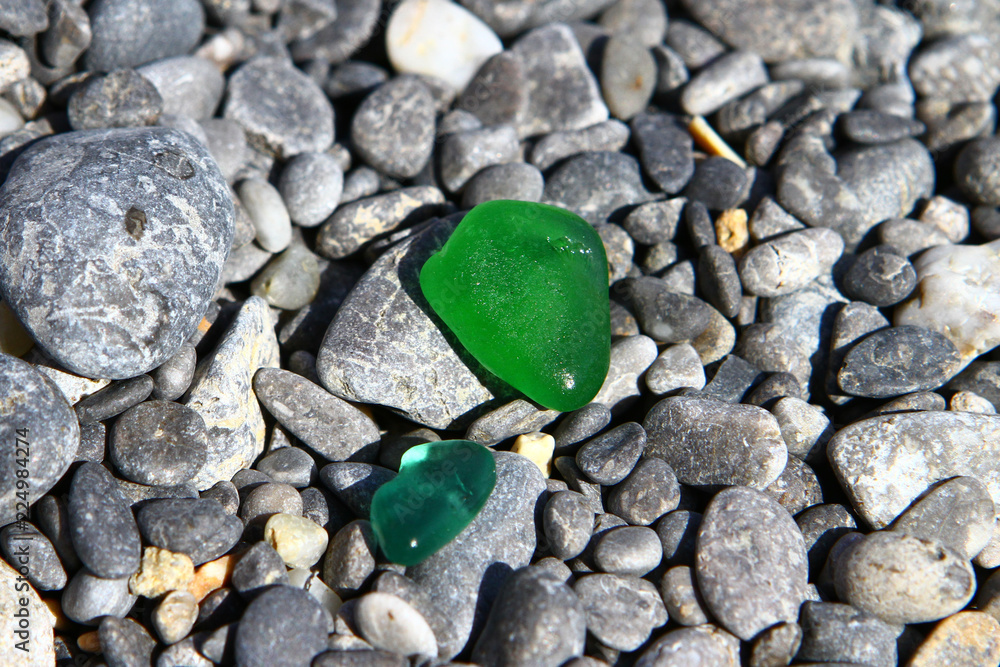 The cute glass shard polished by the sea on dark beach stones - black pebble stones on the beach. Photo of nature The cute glass shard polished by the sea on dark beach stones - black pebble stones on the beach. Photo of nature