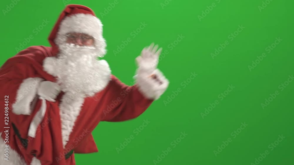 Merry Christmas. Santa Claus in a red suit waving his hand on a green ...