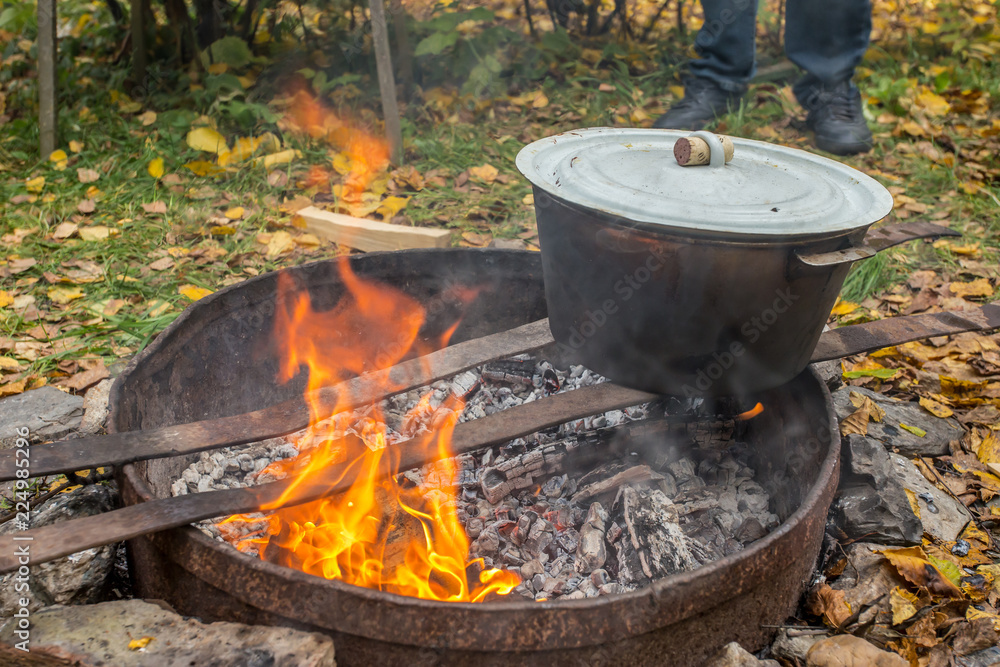 Cooking pilaf on an open fire. Tourist camp in the autumn forest. Cooking pilaf on an open fire. Tourist camp in the autumn forest.