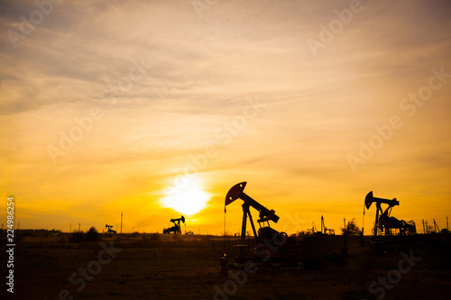 In the evening, the outline of the oil pump. The oil pump, industrial equipment. Oil field site, oil pumps are running. Rocking machines for oil production in a private sector.