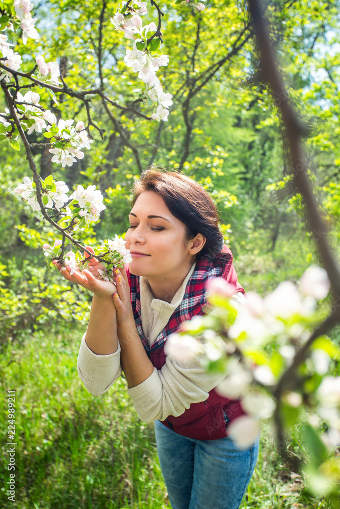 Young beautiful girl sniffs spring flowers in the forest closing her eyes vertically, soft focus Young beautiful girl sniffs spring flowers in the forest closing her eyes vertically, soft focus