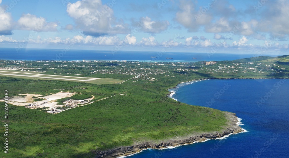 Aerial view of Saipan International Airport runway and Lau Lau Bay seen from the window of an airplane 