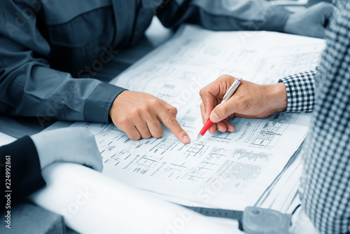 The engineer pointed finger at the paper. Explain the plan structure for the construction business. In order understand the creation of same direction. To complete the job as required by employer.