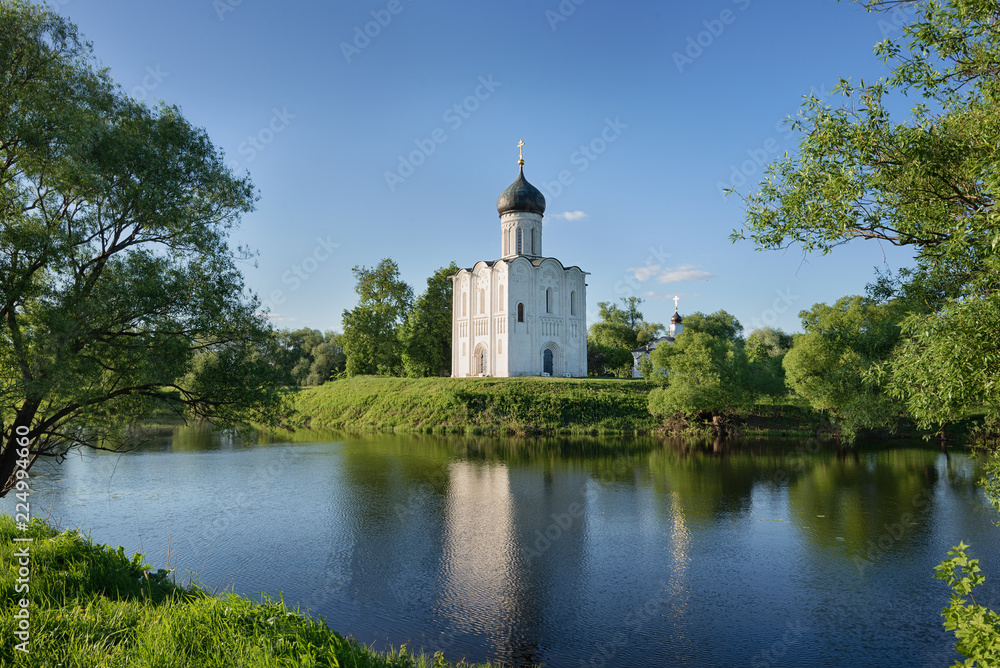 Church of Pokrova na Nerli/ Russia, Vladimir, Bogolubovo - may 2018: facade of church of Pokrova na Nerli in summer day with reflection in water Church of Pokrova na Nerli/ Russia, Vladimir, Bogolubovo - may 2018: facade of church of Pokrova na Nerli in summer day with reflection in water