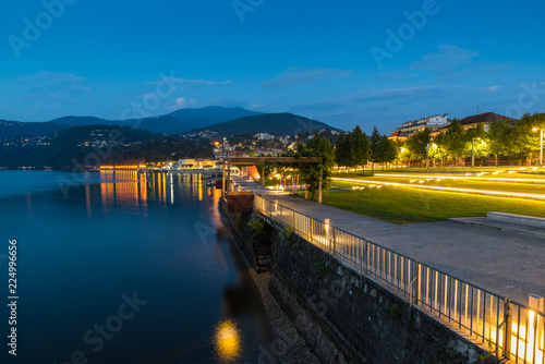 Lakefront promenade at dusk. Lake Maggiore and tourist town of Luino with its beautiful lakefront illuminated on a beautiful summer evening. Big lake in northern Italy