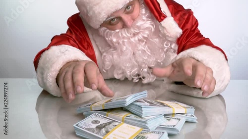 Santa Claus moves a pack of money lying on the table to the camera.
 photo