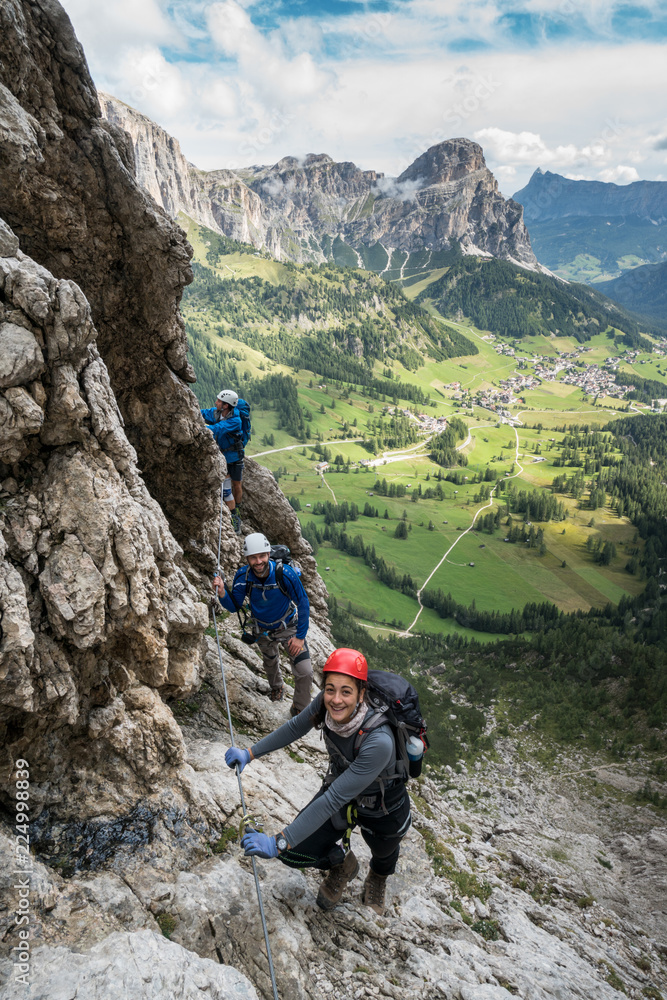 three mountain climbers on a Via Ferrata in the Dolomites in Alta Badia