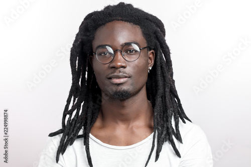 Handsome muscular black man with dreadlocks wearing glasses looking camera on white backgound photo