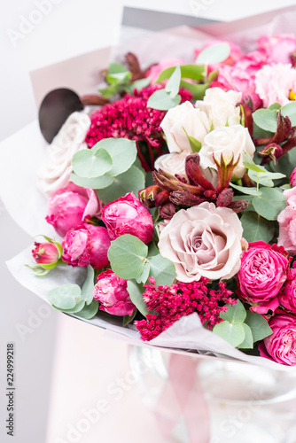 beautiful spring bouquet. flowers arrangement with various of colors in glass vase on pink table. bright room  white wall