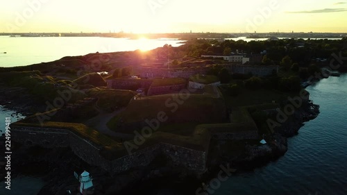 Drone shot of lighthouse and fortified wall in sea during sunset, Helsinki, Suomenlinna, Finland