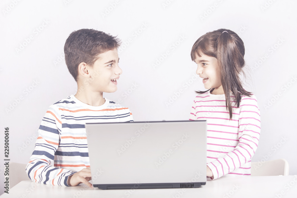 Happy kids using a laptop computer. Education, technology and e-learning concept