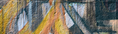 Fragment of graffiti drawings. The old wall decorated with paint stains in the style of street art culture. Colored background texture in warm tones
