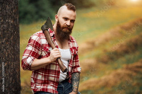 Portrait of bearded woodcutter man with axe outdoor landscape background photo