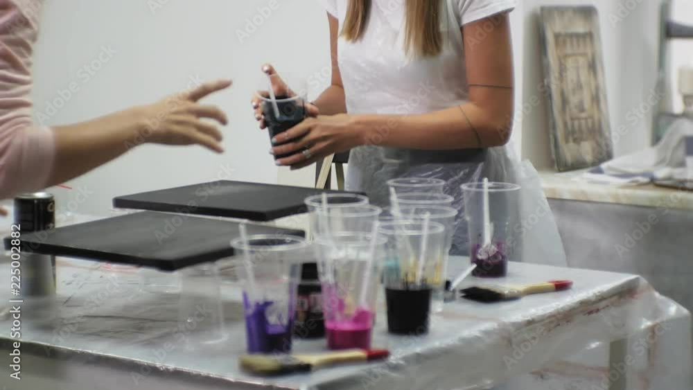 women in an art studio mix paints and draw on canvas in fluid art technique women in an art studio mix paints and draw on canvas in fluid art technique
