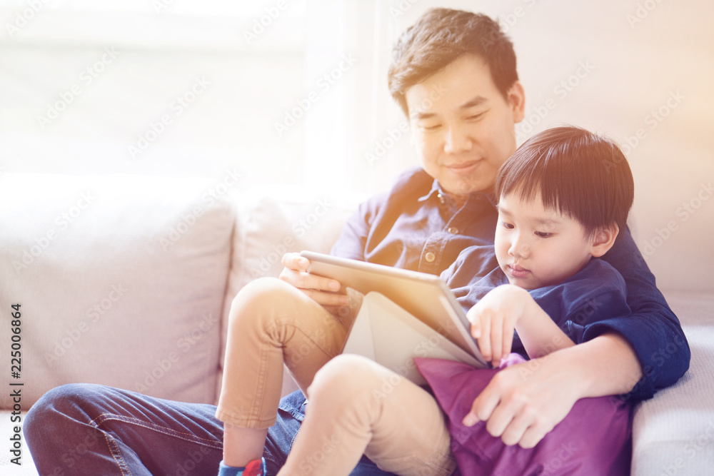 Asian boy is watching a tablet. father taught social learning from around the world to his son. Or what the children do not understand. It is a good family relationship. Father's Day Family concept