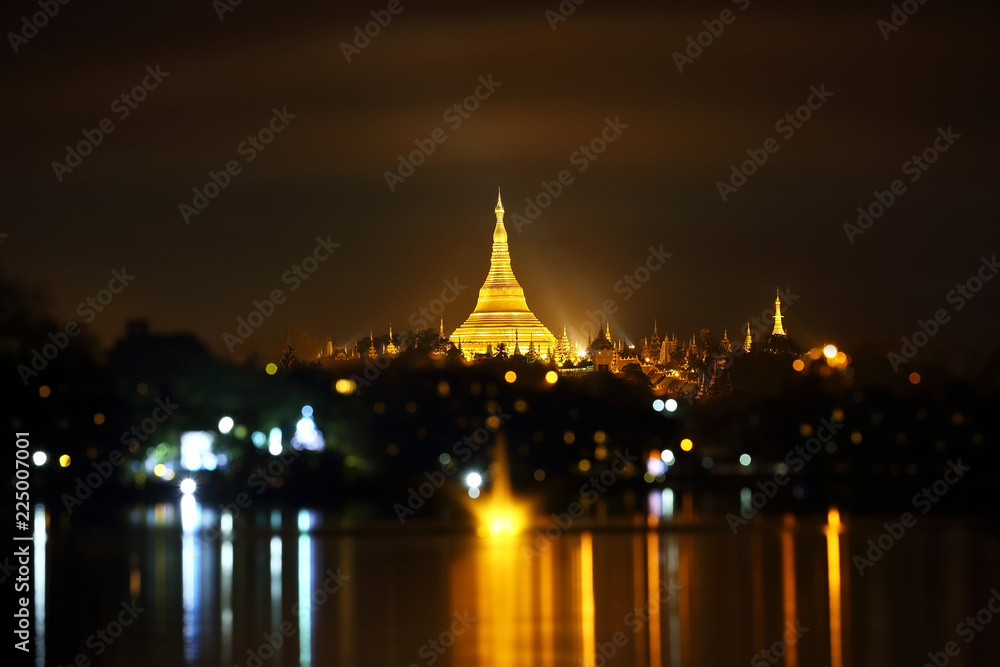 Shwedagon pagoda with bokeh and lake reflection at night, Yangon, Myanmar