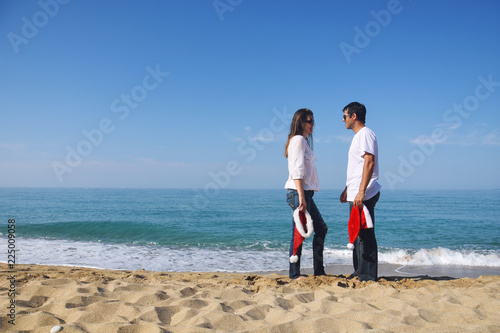 Happy Couple with Santa hat at beach. Young couple in love celebrate Christmas on beach