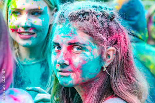  Young energetic teenagers at the festival of paints of holi in Russia. Having fun outdoors. Multicolored powder colors the face.  Closeup portrait