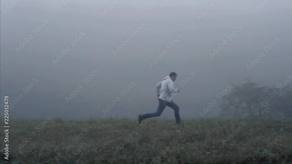 Man running on the grass in the fog,slow mo Man running on the grass in the fog,slow mo