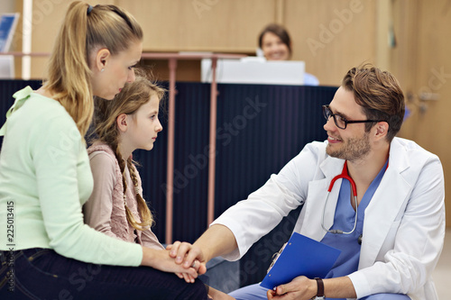 Doctor welcoming mother and daughter in clinic
