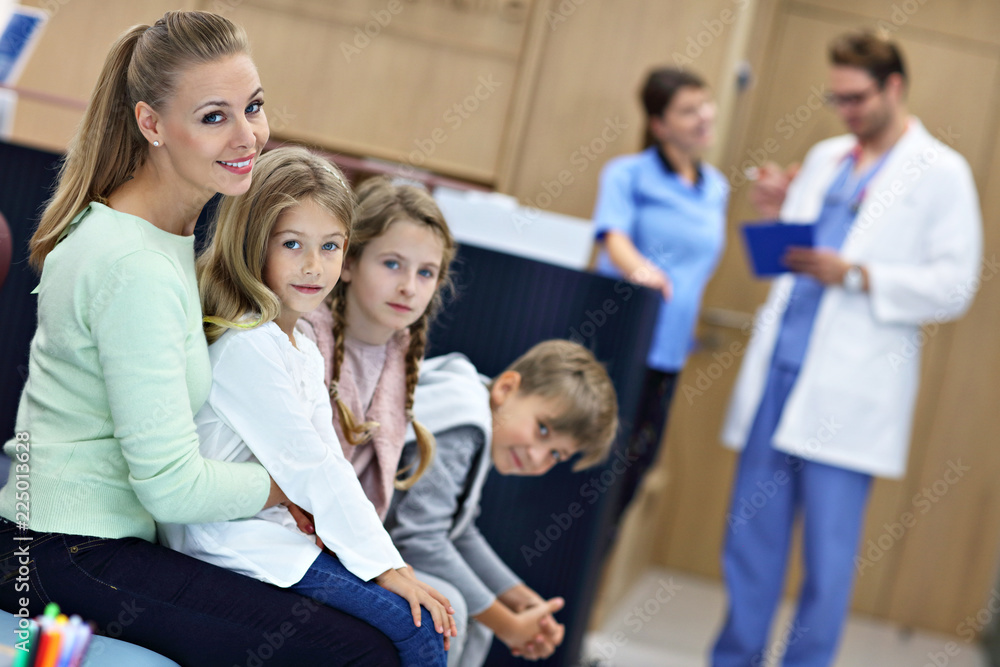 Mother and children waiting in front of registration desk in hospital Mother and children waiting in front of registration desk in hospital