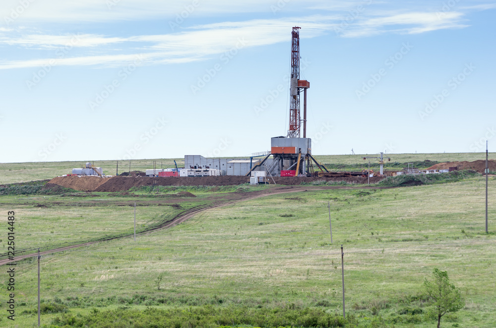 Drilling tower in the steppe. Steppe landscape with drilling rigs and equipment